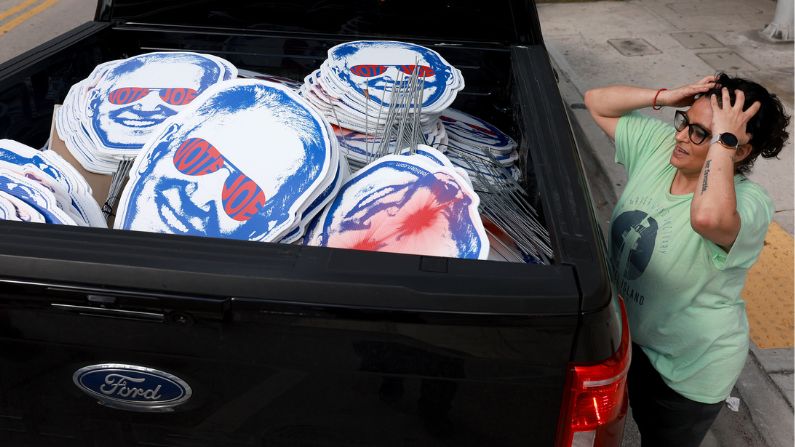 Partidaria de Joe Biden trabaja en la colocación de carteles de campaña de apoyo al presidente en la parte trasera de una camioneta antes del tercer debate primario presidencial republicano de 2023 en Miami, Florida. (Joe Raedle/Getty Images)