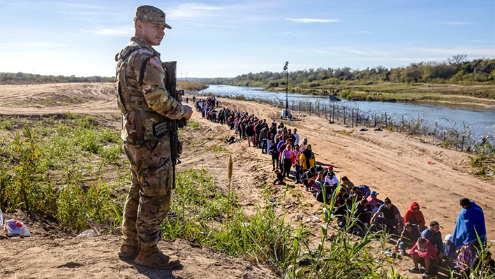 Un soldado de la Guardia Nacional de Texas vigila a un grupo de más de 1000 inmigrantes ilegales que habían cruzado el Río Grande desde México hasta Eagle Pass, Texas, el 18 de diciembre de 2023. (John Moore/Getty Images)
