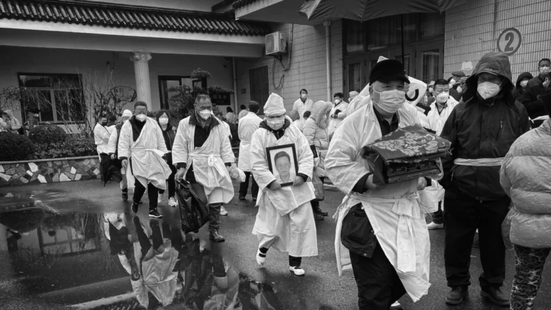 Un doliente lleva los restos cremados de un ser querido mientras él y otros visten la tradicional ropa funeraria blanca, durante un funeral en Shanghai, China, el 14 de enero de 2023. (Kevin Frayer/Getty Images)