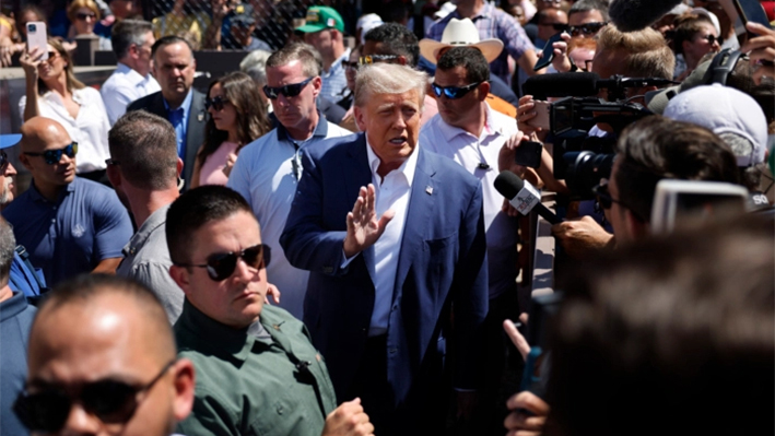 Rodeado de personal de campaña y miembros del Servicio Secreto de EE. UU., el expresidente de EE. UU. Donald Trump (centro) saluda a sus seguidores mientras visita la carpa de los productores de carne de cerdo de Iowa en la Feria Estatal de Iowa en Des Moines, Iowa, el 12 de agosto de 2023. (Chip Somodevilla/Getty Images)
