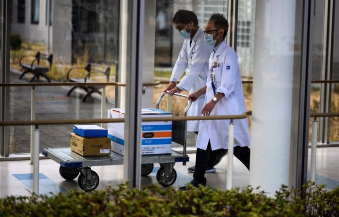 Trabajadores médicos empujan un carrito con cajas que contienen vacunas contra el COVID-19, "proteína de espiga", mientras Japón lanza su campaña de inoculación, en el Hospital Nacional de Tokio en Kiyose, prefectura de Tokio, el 17 de febrero de 2021. (Charly Triballeau/AFP vía Getty Images)