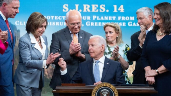 El presidente Joe Biden entrega un bolígrafo a la diputada Nancy Pelosi (2ª izda.), junto a otros miembros de la Cámara, tras firmar un proyecto de ley sobre emisiones de gases de efecto invernadero, en el Eisenhower Executive Office Building, en Washington, el 30 de junio de 2021. (Saul Loeb/AFP/Getty Images)