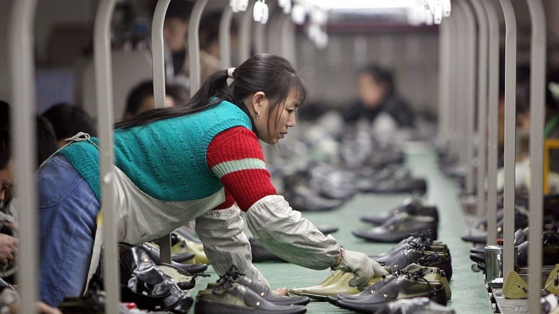 Una trabajadora saca un par de zapatos de una línea de producción en una fábrica situada en la Zona de Desarrollo Industrial de Calzado del Oeste de Chengdu el 19 de enero de 2006 en Chengdu de la provincia de Sichuan, China. (China Photos/Getty Images)