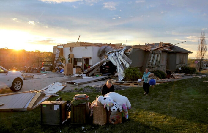 Dos mujeres ayudan a sacar las pertenencias de una amiga de su casa dañada tras el paso de un tornado por la zona en Bennington, Nebraska, el 26 de abril de 2024. (Josh Funk /AP Photo)