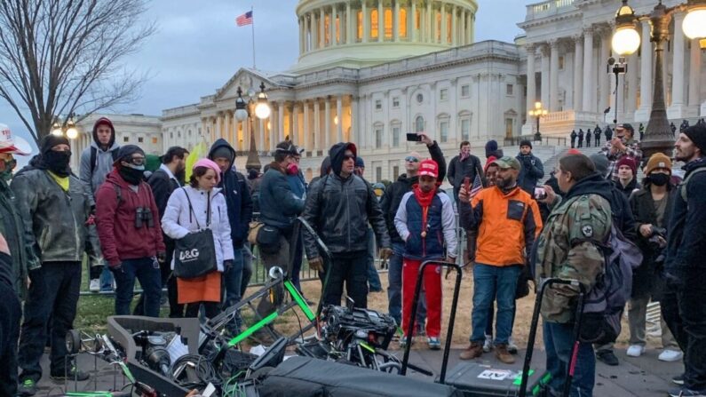Varias personas paradas alrededor de equipos de medios destruidos afuera del Capitolio de los Estados Unidos en Washington DC el 6 de enero de 2021 (Camille Camdessus/AFP vía Getty Images)