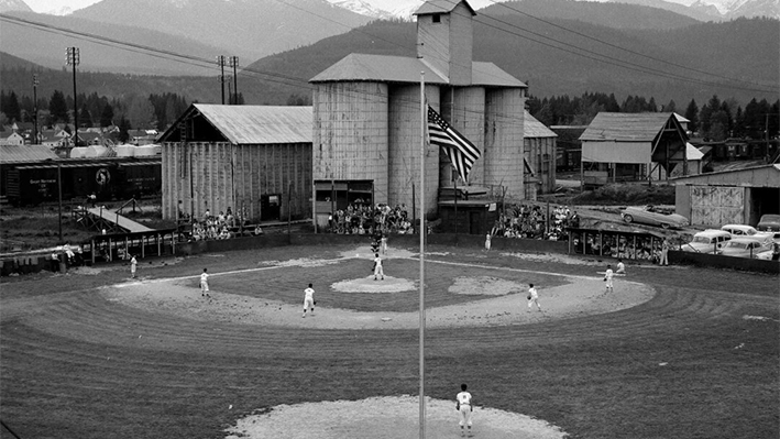 Un campo de béisbol junto a un astillero en Libby, Montana, de la década de 1960, donde se almacenaba vermiculita contaminada con amianto tras ser extraída de una montaña cercana. (The Western News vía AP)
