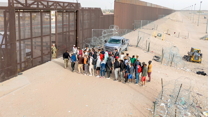 En una vista aérea, unos inmigrantes esperan a ser transportados y procesados tras cruzar la frontera entre Estados Unidos y México en El Paso, Texas, el 13 de marzo de 2024. (John Moore/Getty Images)
