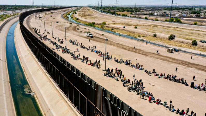 Inmigrantes ilegales esperan junto al muro fronterizo a los agentes de la Patrulla Fronteriza en El Paso, Texas, el 11 de mayo de 2023. (Patrick T. Fallon/AFP vía Getty Images)
