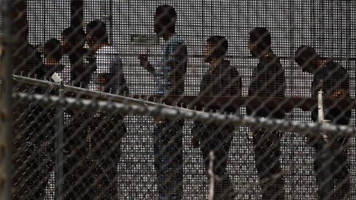 Inmigrantes ilegales esperan junto al muro fronterizo para subir a un autobús tras entregarse a los agentes de la Patrulla Fronteriza de la Oficina de Aduanas y Protección Fronteriza (CBP) en la frontera entre Estados Unidos y México, en El Paso, Texas, el 12 de mayo de 2023. (Patrick T. Fallon/AFP vía Getty Images)
