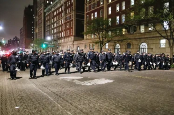 Agentes de la policía de Nueva York en equipo antidisturbios marchan hacia el campus de la Universidad de Columbia, donde los estudiantes pro-Palestina están atrincherados dentro de un edificio y han establecido un campamento, en la ciudad de Nueva York el 30 de abril de 2024. (Kena Betancur/AFP vía Getty Images)