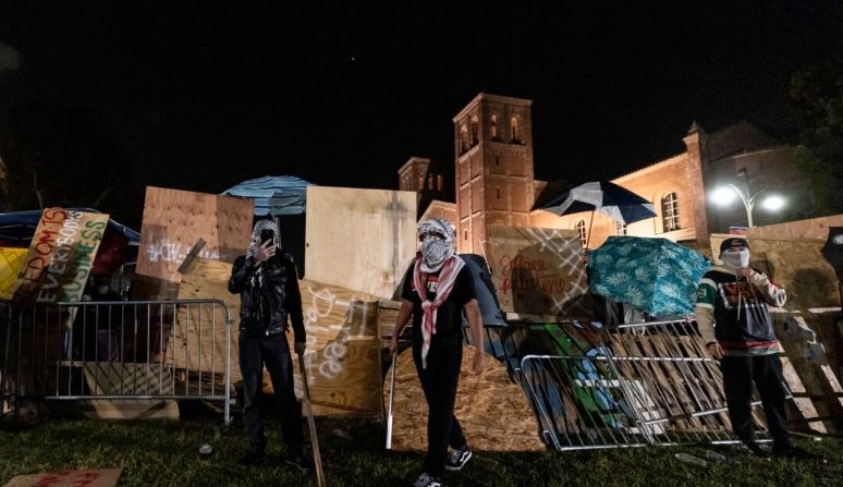 Manifestantes propalestinos reconstruyen la barricada que rodea su campamento en la UCLA tras enfrentamientos con contramanifestantes en Los Ángeles el 1 de mayo de 2024. (Etienne Laurent/AFP vía Getty Images)