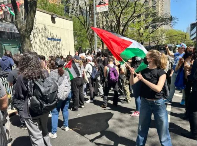 Riley Kerr ondea la bandera palestina en la manifestación de la Universidad de Fordham el 1 de mayo de 2024. (Juliette Fairley/The Epoch Times)