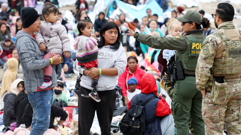 Un agente de la Patrulla Fronteriza de EE. UU. habla con inmigrantes antes de ser transportados desde un campamento improvisado entre muros fronterizos, entre EE. UU. y México, el 13 de mayo de 2023. (Mario Tama/Getty Images)