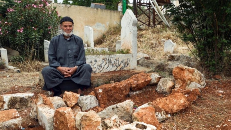 Mohammed Hassan Masto está sentado junto a la tumba de su hermano Lutfi en el pueblo de Qorqanya, una zona rural en el norte de la provincia de Idlib, Siria, el 7 de mayo de 2023. (Omar Albam/Foto AP)