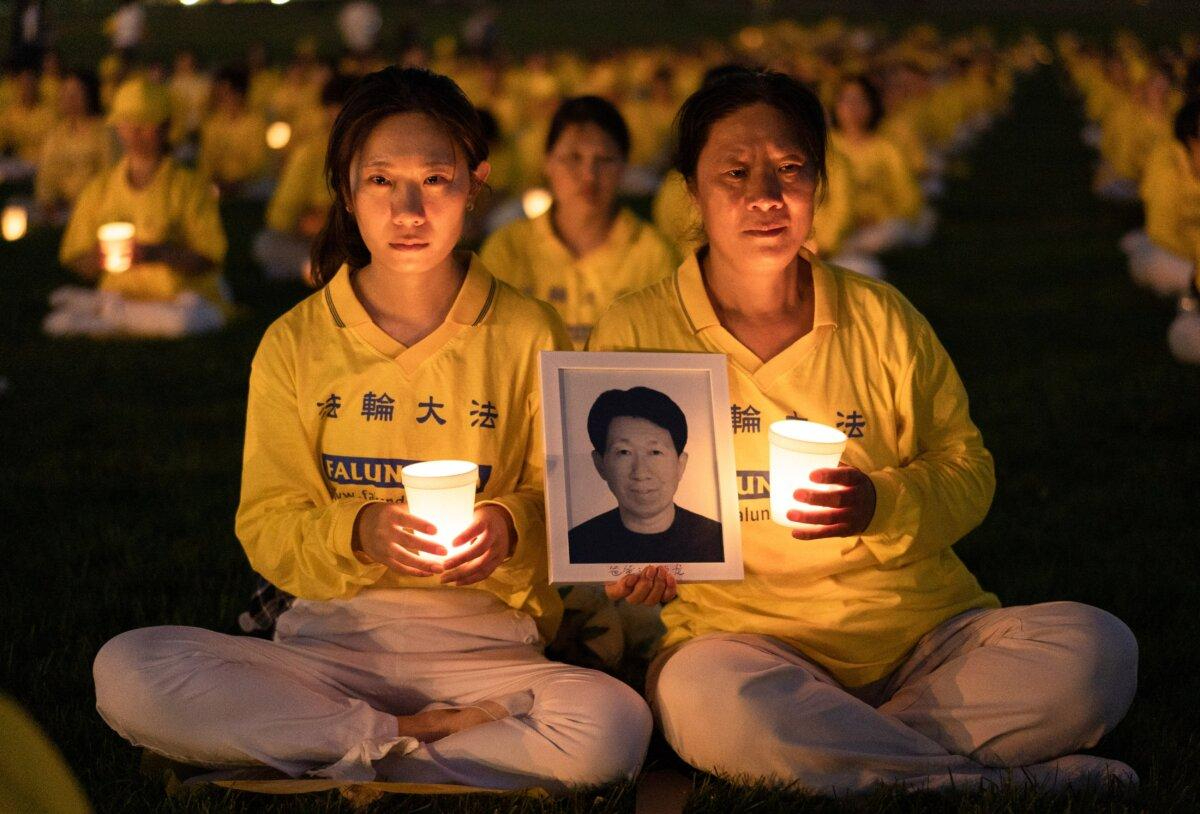 La hija Li Xiaohua y la madre Ju Reihjong asisten a una vigilia con velas para conmemorar a las víctimas de los 23 años de persecución de Falun Gong en China, celebrada en el Monumento a Washington el 21 de julio de 2022. Ju sostiene una foto de su marido y padre de Li, Li Delong, que murió en la persecución.(Samira Bouaou/The Epoch Times)