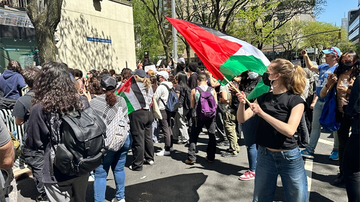 Riley Kerr ondea la bandera palestina en la manifestación de la Universidad de Fordham el 1 de mayo de 2024. (Juliette Fairley/The Epoch Times)
