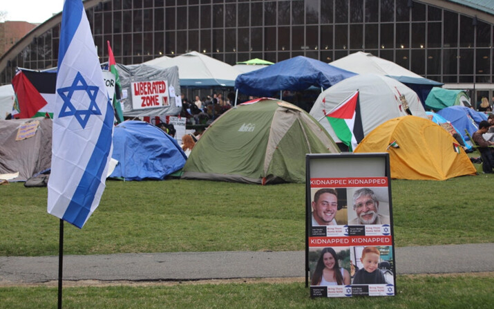 Una bandera israelí colocada junto a carteles de rehenes israelíes tras los ataques de Hamás del 7 de octubre se encuentra cerca de un campamento pro-palestino, en el MIT, en Boston, Massachusetts, el 29 de abril de 2024. (Cortesía de Alice Giordano)
