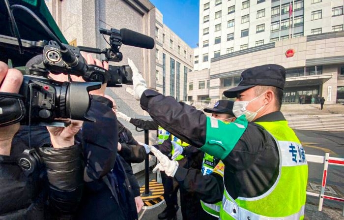 Un policía tapa una cámara para impedir que los periodistas graben imágenes en el exterior de la Corte Popular del Nuevo Distrito de Pudong, en Shanghái, donde el periodista ciudadano chino Zhang Zhan sería juzgado el 28 de diciembre de 2020. (Leo Ramirez/AFP vía Getty Images)