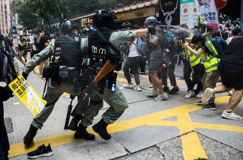 Policías antidisturbios rocían con gas pimienta a periodistas en el 23 aniversario del traspaso d Hong Kong, de Gran Bretaña a China, mientras los manifestantes se reúnen para una concentración contra la nueva Ley de Seguridad Nacional el 1 de julio de 2020. (Dale De La Rey/AFP vía Getty Images)