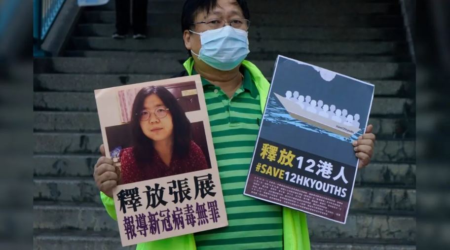 Un activista pro-democracia sostiene una pancarta instando a las autoridades chinas a liberar a la periodista ciudadana china Zhang Zhan y a 12 hongkoneses detenidos frente a la oficina de enlace del gobierno central chino, en Hong Kong, el 28 de diciembre de 2020. (Kin Cheung/Foto AP)