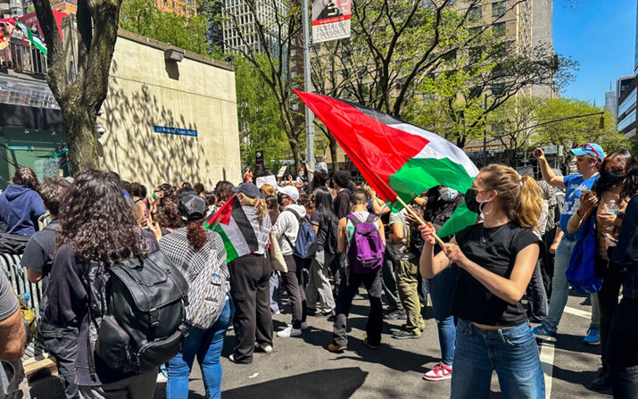 Riley Kerr ondea la bandera palestina en la concentración de la Universidad de Fordham, en Nueva York, el 1 de mayo de 2024. (Juliette Fairley/The Epoch Times)

