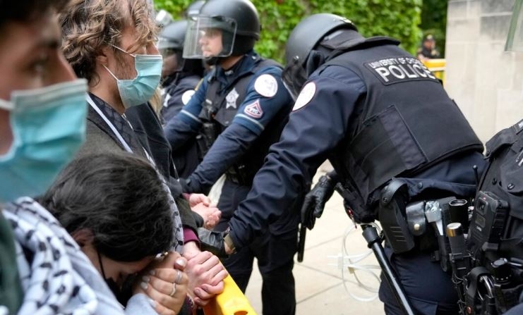 Una manifestante pro-palestina apoya la cabeza sobre sus manos entrelazadas mientras se para ante los agentes de policía de la Universidad de Chicago el 7 de mayo de 2024. (Charles Rex Arbogast/Foto AP)