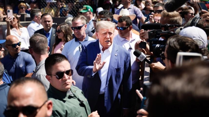 Rodeado de personal de campaña y miembros del Servicio Secreto de Estados Unidos, el expresidente de Estados Unidos Donald Trump (C) saluda a sus partidarios mientras visita la Carpa de Productores de Cerdo de Iowa en la Feria Estatal de Iowa en Des Moines, Iowa, el 12 de agosto de 2023. (Chip Somodevilla/Getty Images)