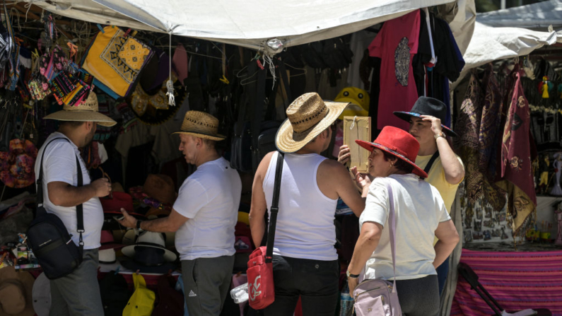 Turistas extranjeros compran sombreros para protegerse del sol durante una ola de calor que azota Ciudad de México (México) el 16 de abril de 2024. (Yuri Cortez/AFP vía Getty Images)