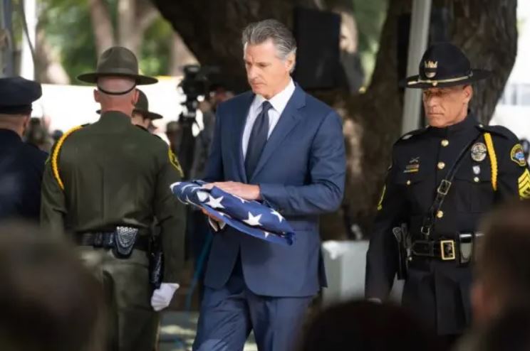 El gobernador Gavin Newsom sostiene una bandera de EE. UU. en la 46ª Ceremonia Anual de Conmemoración de los Oficiales de Paz de California en Sacramento el 6 de mayo de 2024. (Oficina del gobernador Gavin Newsom)