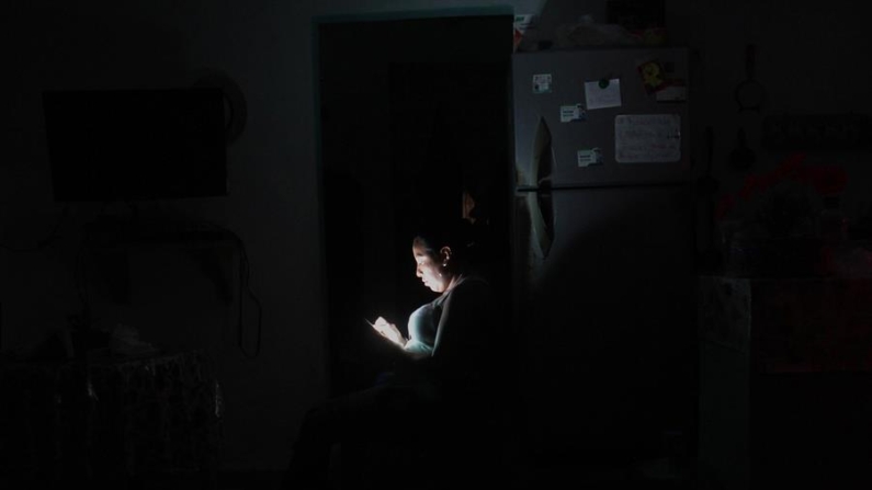 Imagen de archivo de una mujer que observa su celular durante un apagón en el balneario de Cancún en el estado de Quintana Roo (México). EFE/Alosnso Cupul