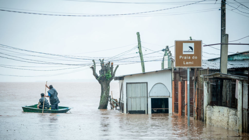 Dos hombres montan un bote en Praia do Lami mientras llueve en una zona afectada por las inundaciones el 10 de mayo de 2024 en Porto Alegre, Brasil. (Jefferson Bernardes/Getty Images)