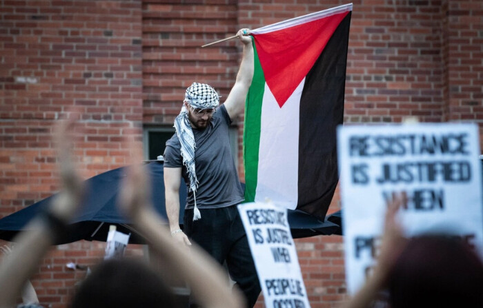 Un manifestante sostiene en alto una bandera palestina mientras cientos de personas se concentran en el campamento de solidaridad con Gaza de la Universidad George Washington en respuesta a la invasión israelí de Rafah, Washington, D.C., el 7 de mayo de 2024. (Allison Bailey/Middle East Images/AFP/Getty Images)