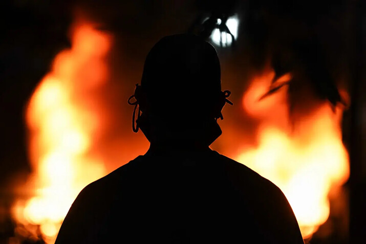 La silueta de un hombre con una mascarilla frente a un coche de policía en llamas en Atlanta, Georgia, el 29 de mayo de 2020. (Elijah Nouvelage/Getty Images)