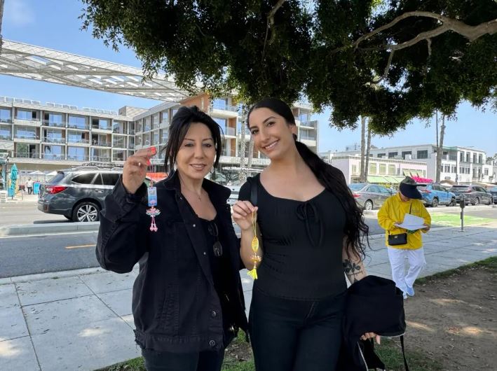 Dos visitantes sostienen decoraciones de flores de loto en la 25ª celebración del Día de Falun Dafa en Santa Mónica, California, el 12 de mayo de 2024. (Linda Jiang/The Epoch Times)