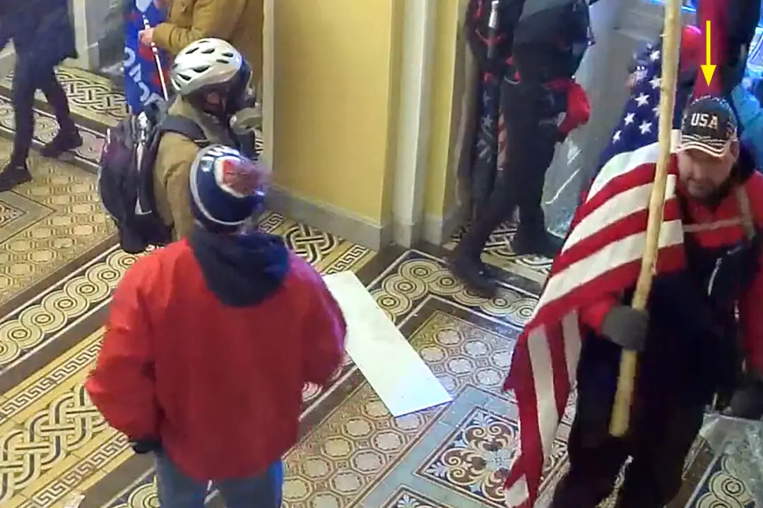 William Pope de Topeka, Kansas, lleva una bandera estadounidense dentro de la puerta del ala del Senado en el Capitolio de EE. UU. el 6 de enero de 2021. (Policía del Capitolio de EE. UU./Captura de pantalla vía The Epoch Times)