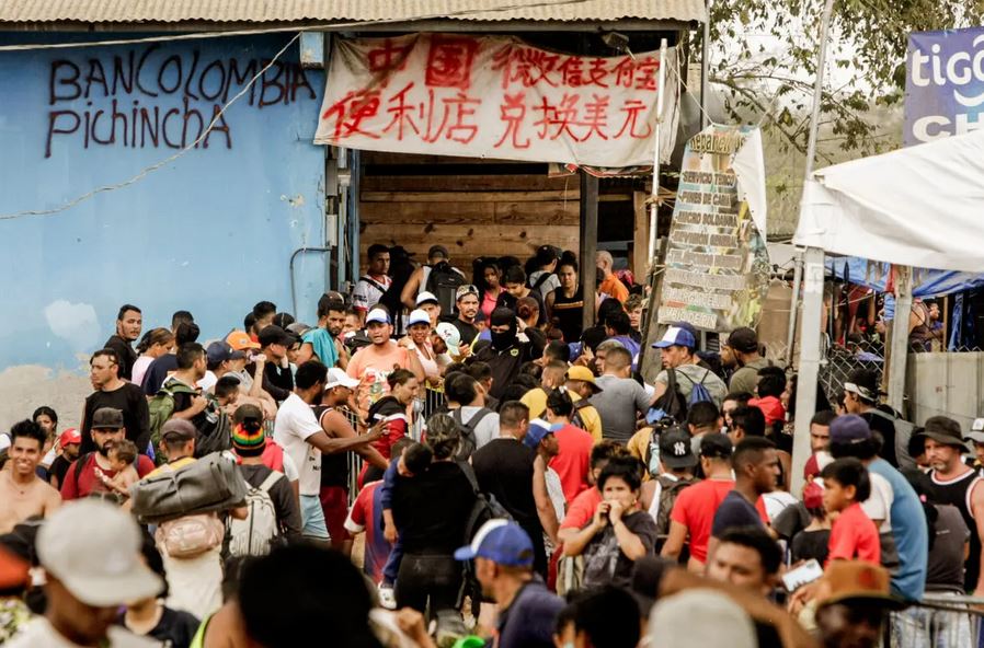 Migrantes hacen cola para trámites de inmigración en Lajas Blancas mientras comerciantes ofrecen servicios tanto en español como en chino en Panamá el 17 de febrero de 2024. (Bobby Sanchez para The Epoch Times)