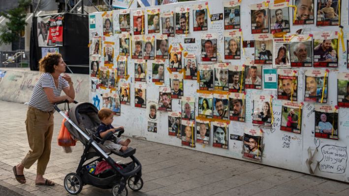 Los transeúntes observan las fotos de los rehenes retenidos en la Franja de Gaza que están pegadas a las paredes de una plaza conocida como Plaza de los Rehenes en Tel Aviv, Israel, el viernes 17 de mayo de 2024. (AP Photo/Oded Balilty)