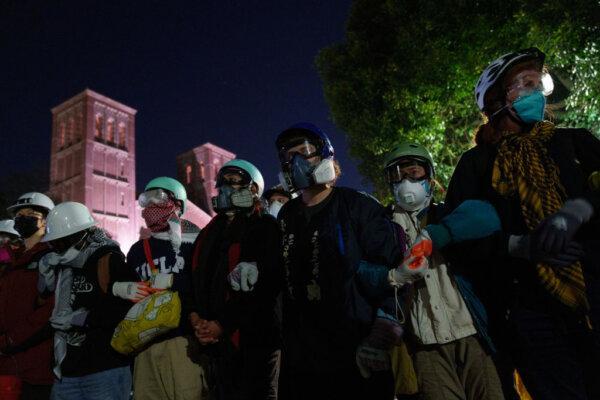 Manifestantes pro-Palestina enlazan sus brazos frente a miembros de las fuerzas policiales en una acampada en UCLA en Los Ángeles el 2 de mayo de 2024. (Eric Thayer/Getty Images)