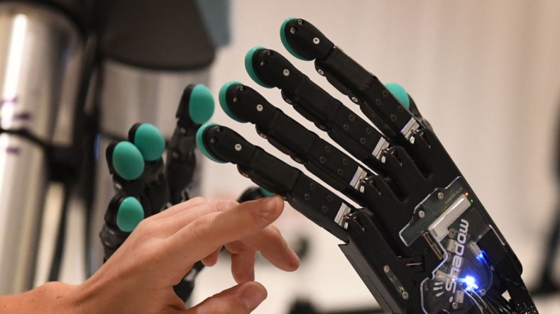 Una mujer toca una mano robótica producida por la empresa Syntouch durante la conferencia Amazon Re:MARS sobre robótica e inteligencia artificial en el Hotel Aria en Las Vegas, Nevada, el 5 de junio de 2019. (MARK RALSTON/AFP vía Getty Images)
