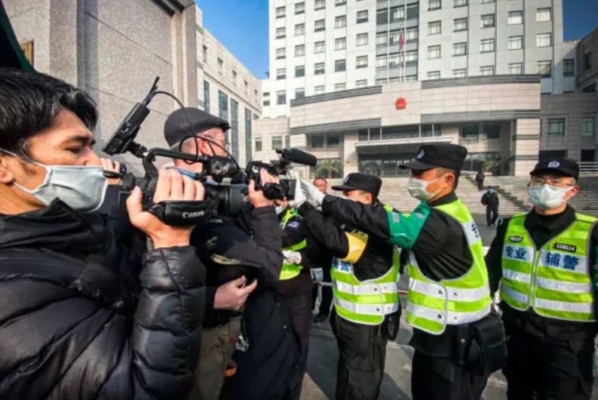 La policía intenta impedir que los periodistas graben imágenes en el exterior del Tribunal Popular del Nuevo Distrito de Pudong de Shanghái, donde fue condenada la periodista ciudadana Zhang Zhan, en Shanghái, el 28 de diciembre de 2020. (Leo Ramirez/AFP vía Getty Images)