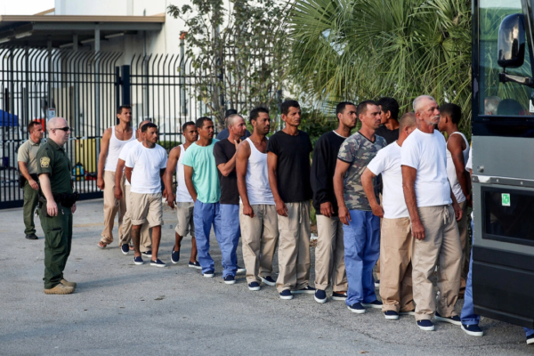 Extranjeros ilegales procedentes de Cuba hacen fila para subir a un autobús y ser conducidos a una estación de Aduanas y Protección Fronteriza de EE. UU. mientras son procesados en Marathon, Florida, el 5 de enero de 2023. (Joe Raedle/Getty Images)