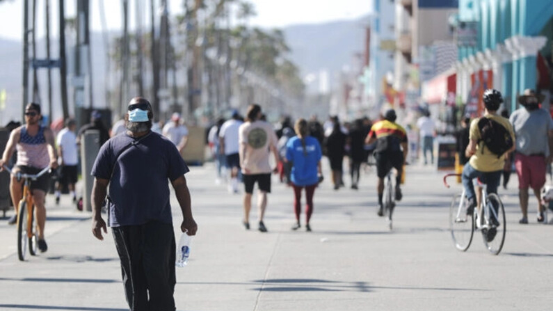 Un hombre con mascarilla camina por el paseo marítimo de Venice Beach el día en que el condado de Los Ángeles reabrió sus playas, que habían permanecido cerradas debido a la pandemia de COVID-19, en California, el 13 de mayo de 2020. (Mario Tama/Getty Images)