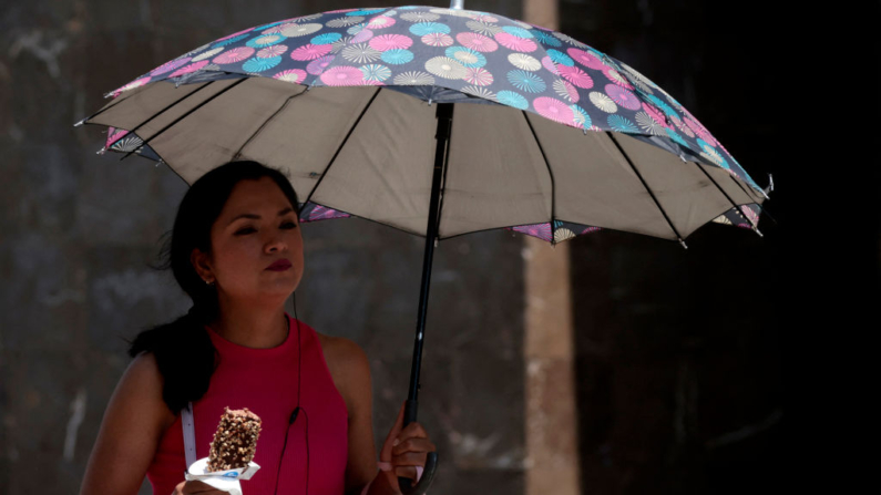 Una mujer camina llevando un paraguas para protegerse del sol durante la ola de calor que azota el país en Guadalajara, estado de Jalisco, México, el 23 de mayo de 2024. (Ulises Ruiz/AFP vía Getty Images)
