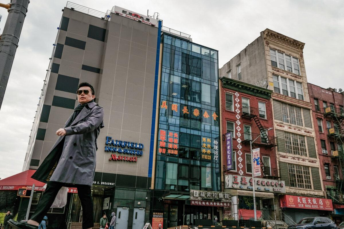 Varias personas caminan junto a un edificio (C) que se sospecha que es una comisaría de la policía secreta controlada por Beijing y utilizada para reprimir a los disidentes que viven en Estados Unidos, en el barrio chino de Nueva York, el 18 de abril de 2023. (Spencer Platt/Getty Images)