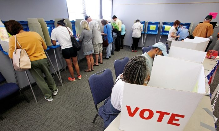 Un grupo de personas deposita su boleta electoral para las elecciones generales de 2016 en un colegio electoral repleto de gente mientras comienza la votación anticipada en Carrboro, Carolina del Norte, el 20 de octubre de 2016. (Jonathan Drake/Reuters)
