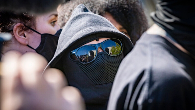 Hombres y mujeres vestidos de negro asistieron a una protesta en Los Ángeles, California, el 20 de octubre de 2021. (John Fredricks/The Epoch Times)
