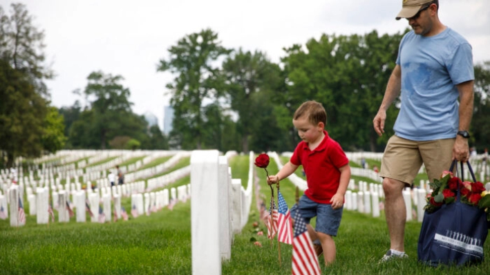 Matthew Murphy, de 4 años, coloca una rosa en una lápida junto a su padre, Kevin Murphy, de Springfield, Virginia, durante un evento de voluntarios en el Cementerio Nacional de Arlington en Arlington, Virginia, antes del Día de la Recordación el 26 de mayo de 2019. (Tom Brenner/Getty Images)