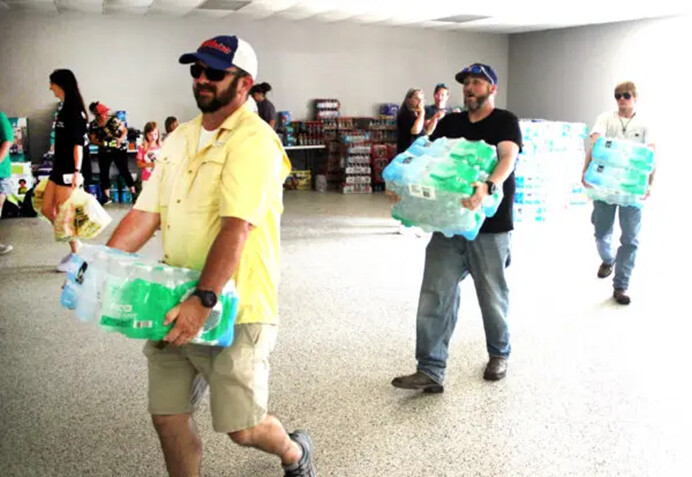 Voluntarios llevan cajas de agua embotellada al centro comunitario de Valley View, Texas, el 16 de mayo de 2024. (Michael Clements/The Epoch Times)