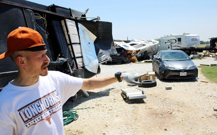 Brandon Finney frente a su caravana volcada mientras relata el paso del tornado que azotó la noche anterior el parque de caravanas en el que vive, el 26 de mayo de 2024. (Michael Clements/The Epoch Times)
