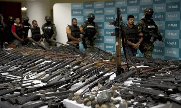 Marines mexicanos escoltan a cinco presuntos narcotraficantes del cártel de la droga de los Zetas ante un lanzacohetes RPG-7, granadas de mano, armas de fuego, cocaína y uniformes militares incautados a presuntos miembros del cártel de narcotraficantes de los Zetas y presentados a la prensa el 9 de junio de 2011. (YURI CORTEZ/AFP/Getty Images)